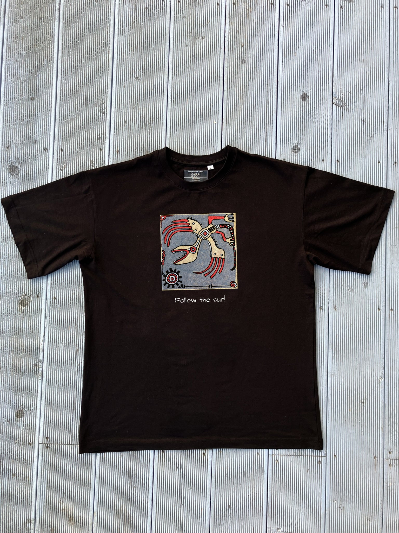 Czarna koszulka oversize unisex z nadrukiem grafiki z ręcznie malowanego kafla "Follow the sun". Grafika w stylu etno z motywem czerwonego stworzenia i napisem pod spodem.