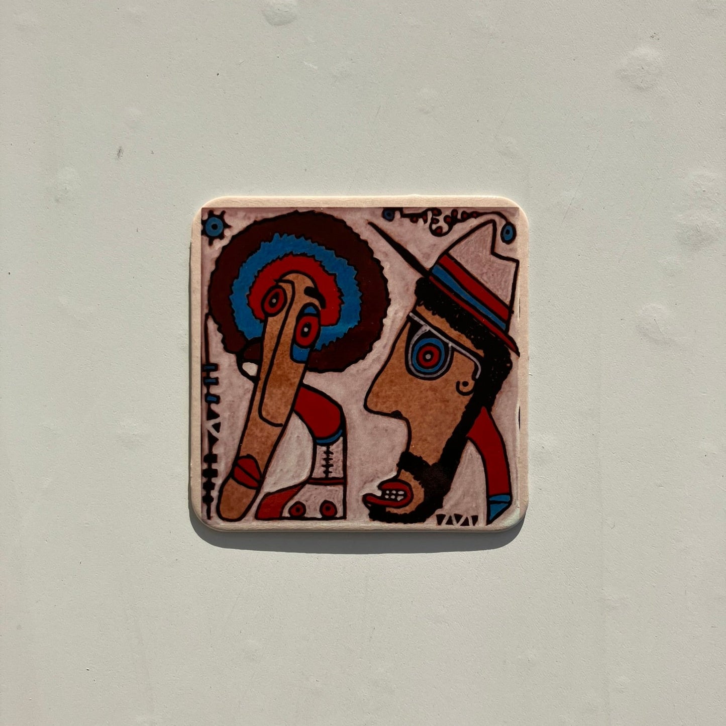 Korkowa podkładka pod kubek z artystycznym wzorem dwóch twarzy na jasnoszarym tle.