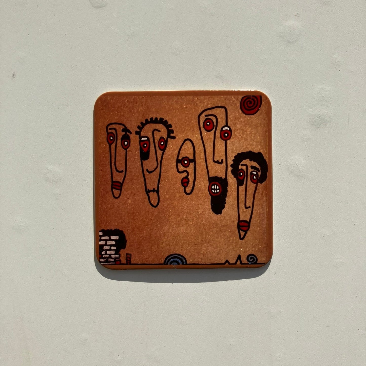 Wooden coaster with cartoon faces on a light gray background