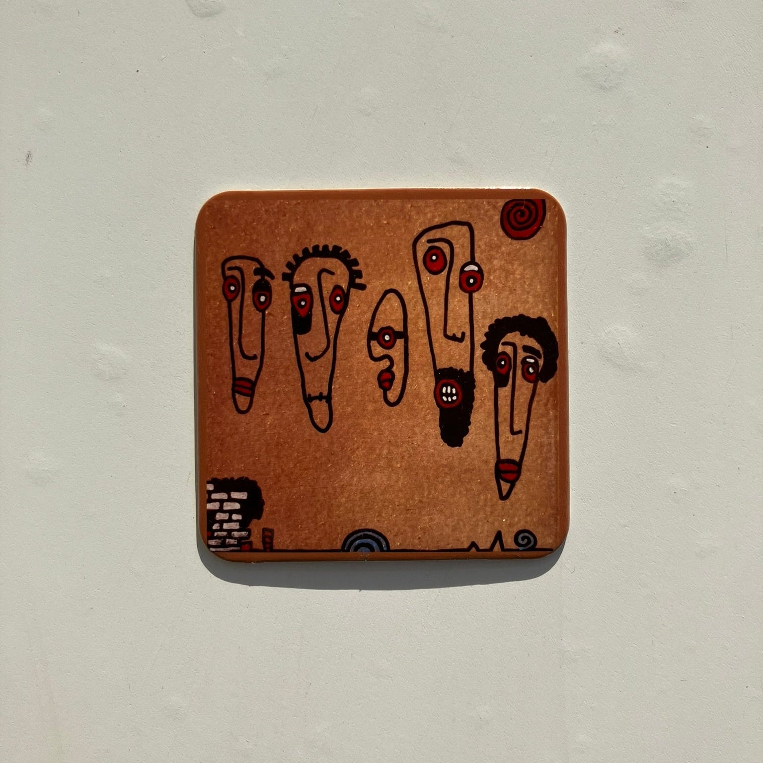 Wooden coaster with cartoon faces on a light gray background