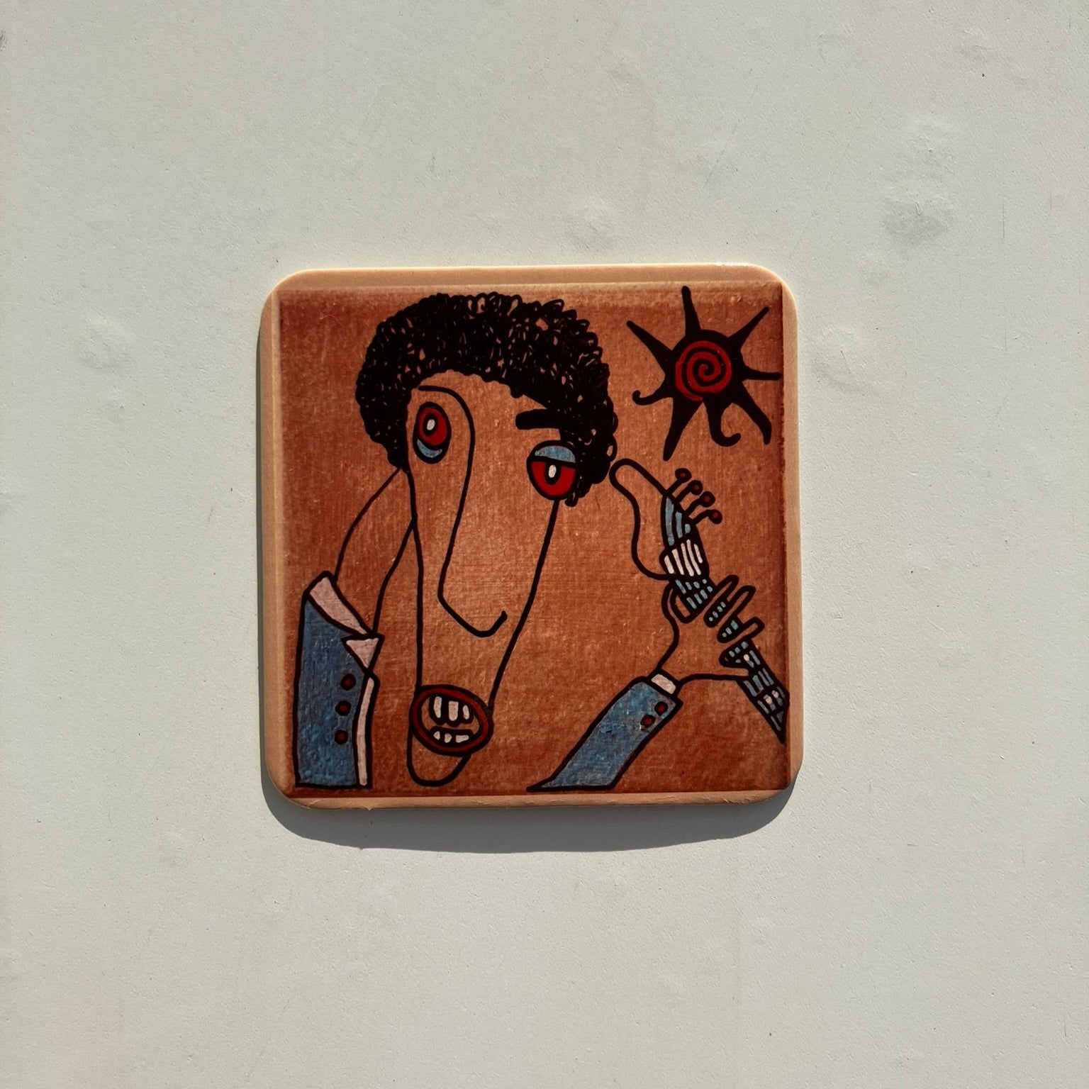 Korkowa podkładka pod kubek z artystyczną, karykaturalną wizją basisty na jasnoszarym tle.