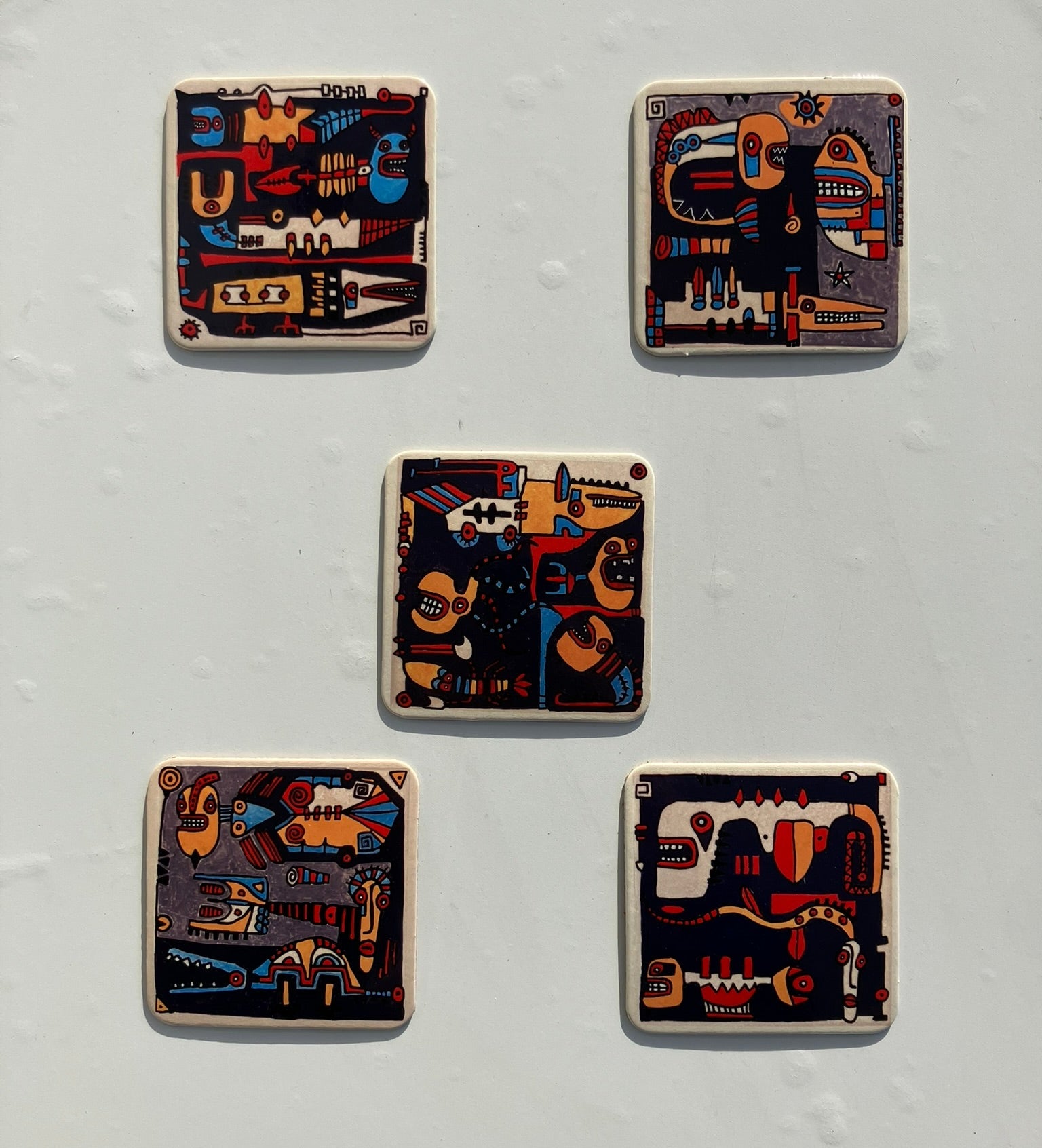 Pięć podkładek z artystycznym, abstrakcyjnym designem na jasnym tle