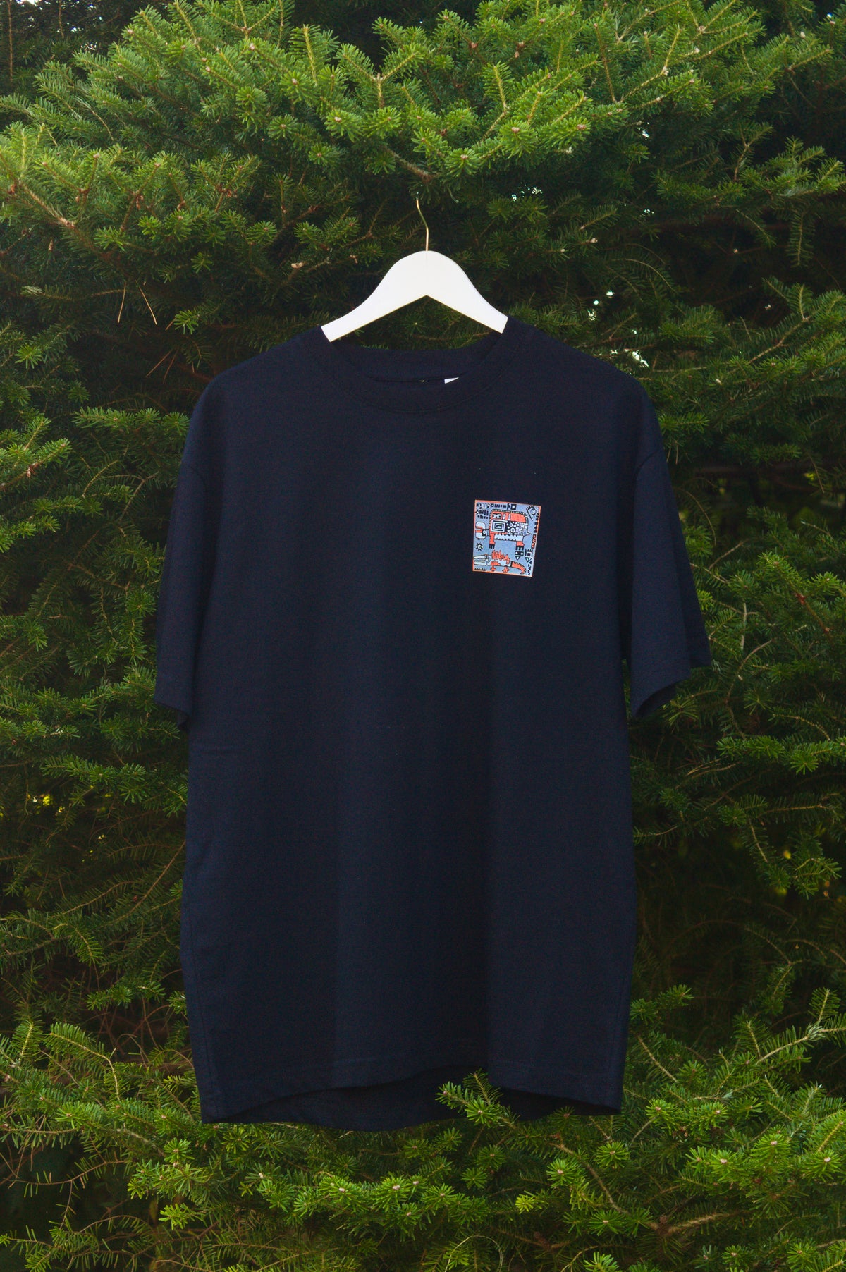 Czarny t-shirt z małą, kolorową grafiką abstrakcyjną umieszczoną na piersi.