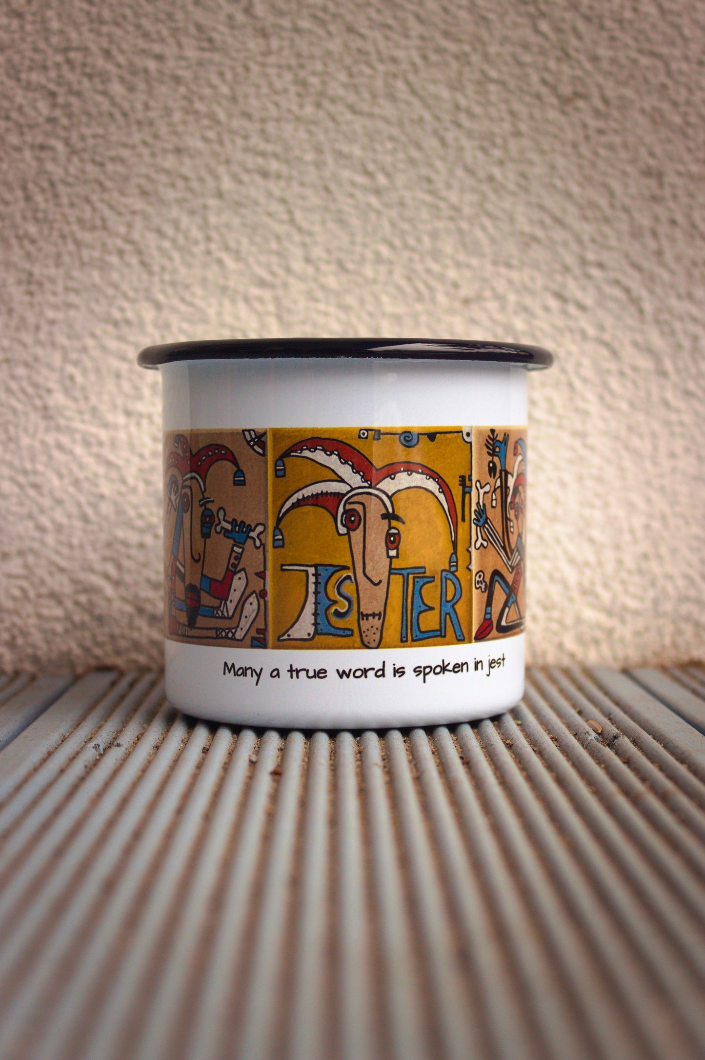 Kubek stalowy retro z grafiką błazna i napisem „Many a true word is spoken in jest”.