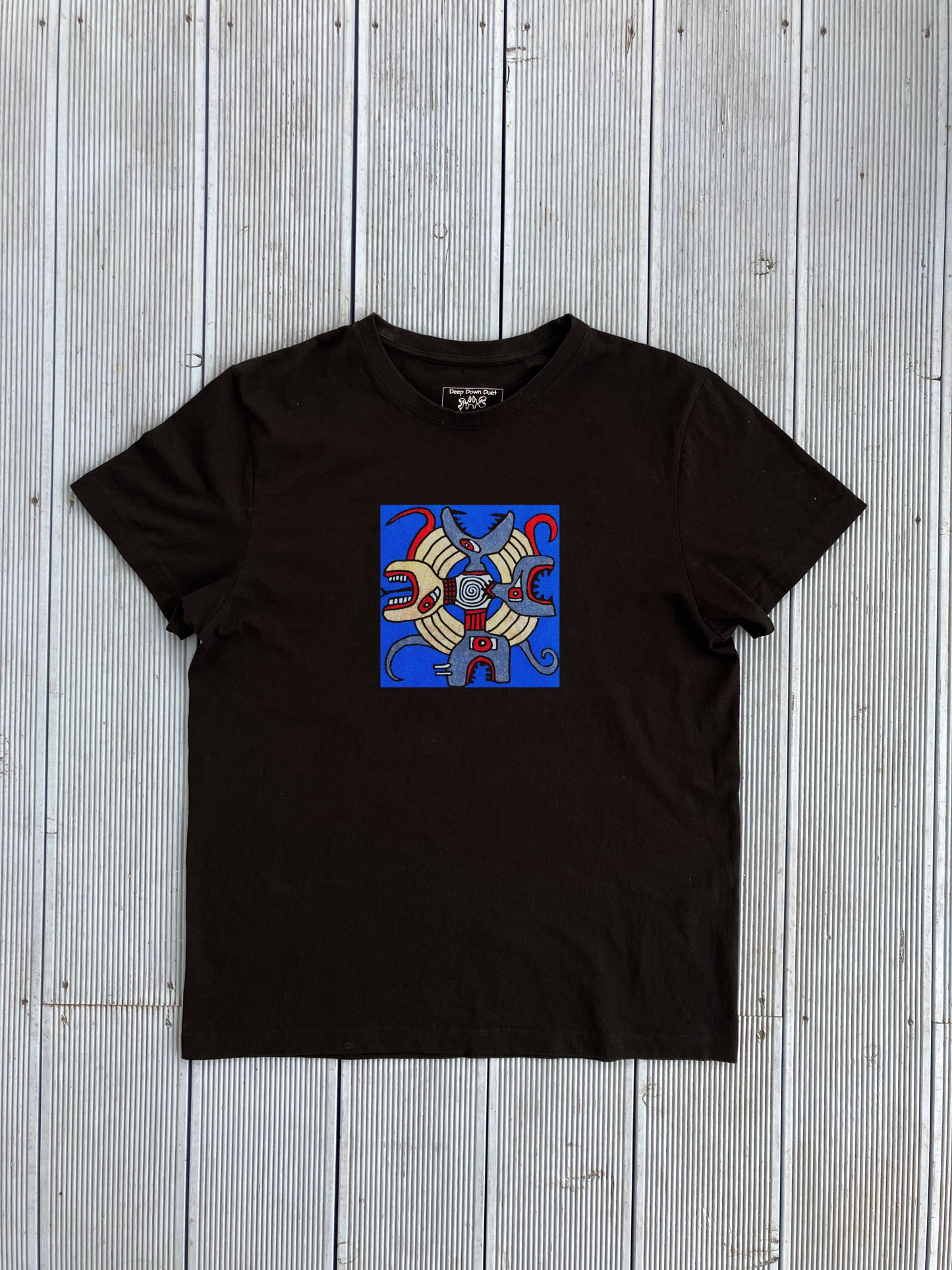 Czarna koszulka unisex z artystycznym nadrukiem "The Kingdom". Kolorowy wzór na niebieskim tle z motywem abstrakcyjnych zwierząt ułożonych w formie mandali.