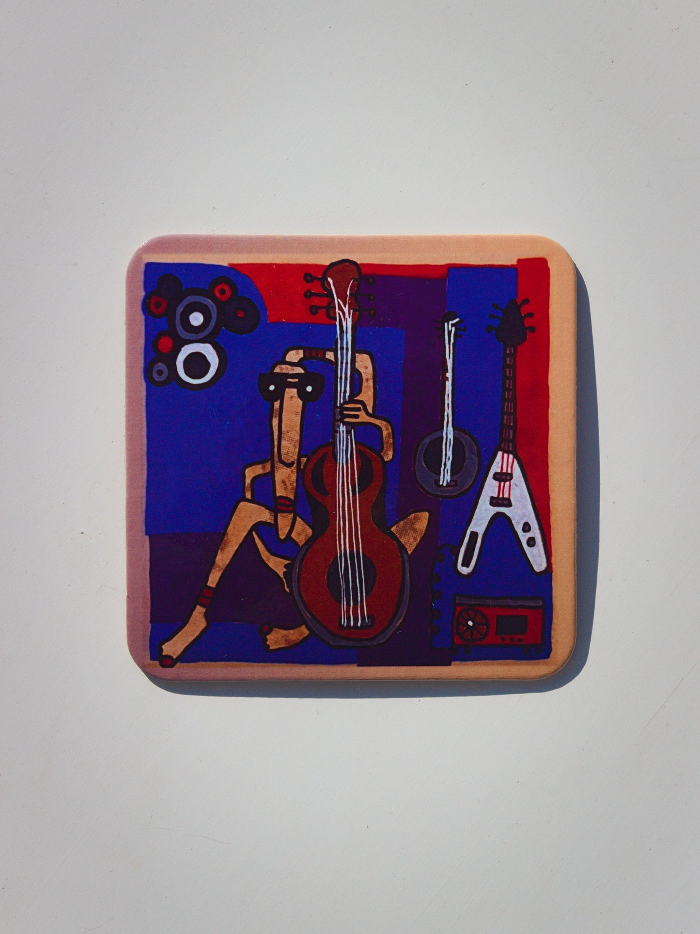 Podkładka korkowa z surrealistyczną grafiką muzykantki grającej na gitarze w otoczeniu innych gitar, ciemnoniebieskie tło.