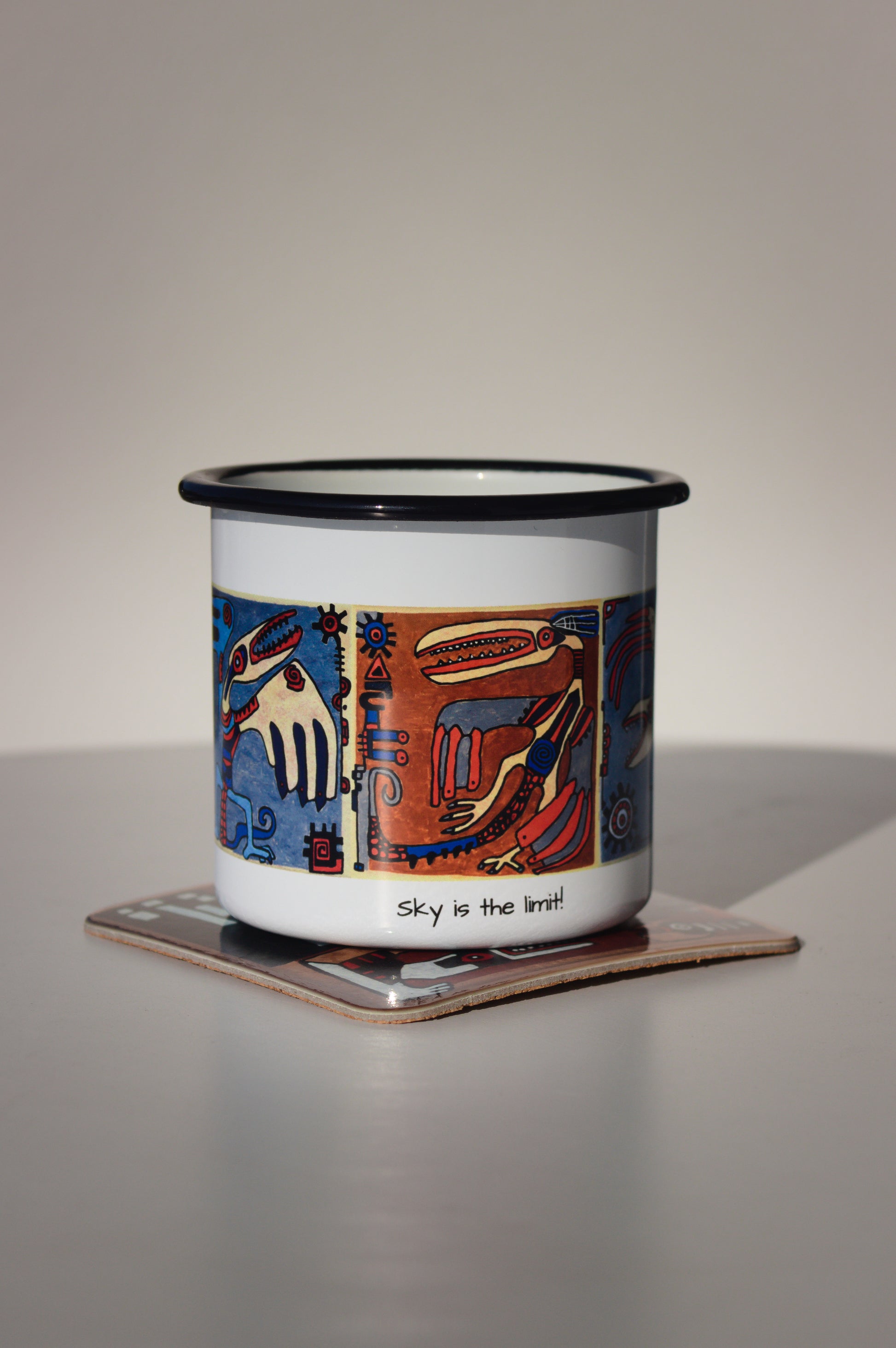 Kubek stalowy „Sky is the limit!” na dopasowanej podkładce z motywem kaflowym, profesjonalne zdjęcie produktowe lifestyle.