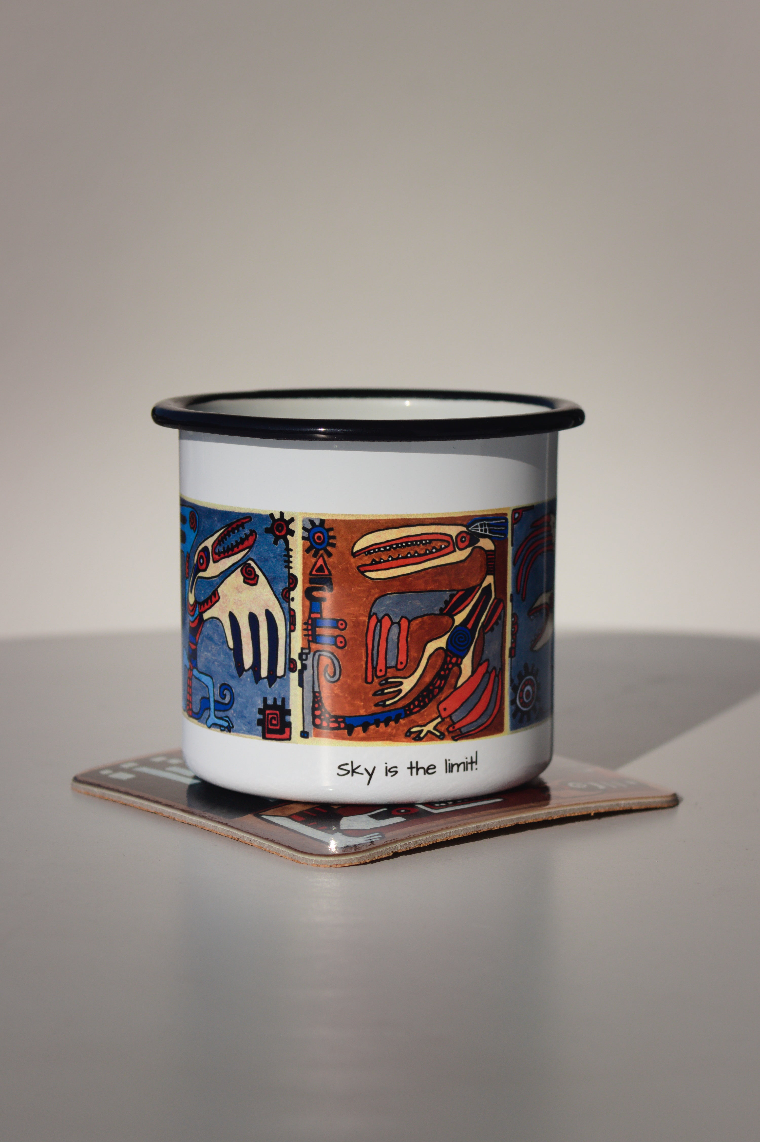 Kubek stalowy „Sky is the limit!” na dopasowanej podkładce z motywem kaflowym, profesjonalne zdjęcie produktowe lifestyle.